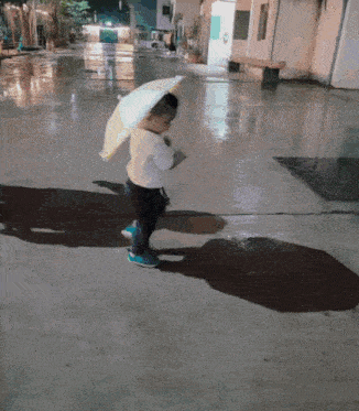 a little boy is walking with an umbrella in his hand