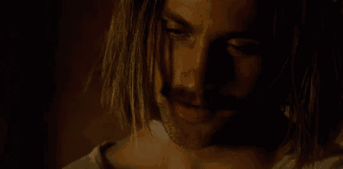 a close up of a man 's face with long hair and a beard .