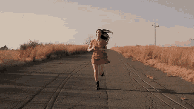 a woman in a red dress running down a road