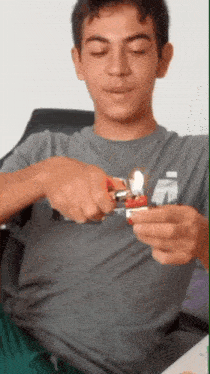 a young man in a grey shirt is lighting a lighter with the letter a on it