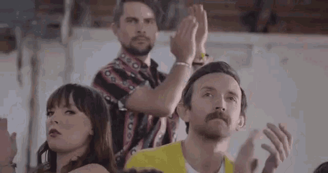a group of people are clapping their hands in a crowd .