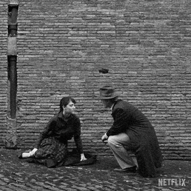a man and a woman are sitting in front of a brick wall with netflix written on the bottom right