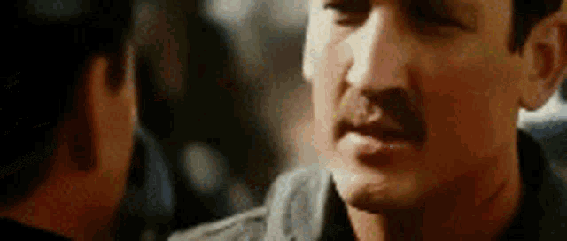 a man with a mustache is looking at another man with a beard .