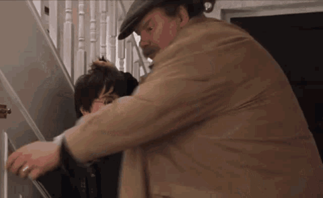 a man in a hat is holding a child 's head while standing on a set of stairs .
