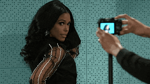 a woman in a black dress is being photographed by a man