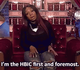 a woman is sitting on a red couch and saying i 'm the hbic first and foremost