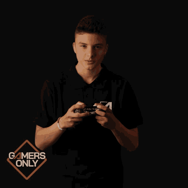 a man in a black shirt with the letter a on it stands in front of a gamers only sign
