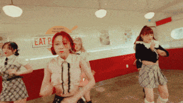a group of women are dancing in front of a sign that says eat p