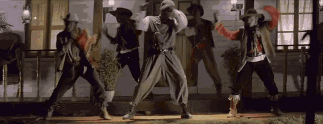 a group of men in cowboy outfits are dancing on a porch