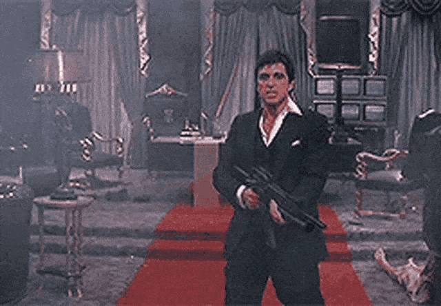 a man in a suit is holding a gun that is shooting a heart shaped fireball .