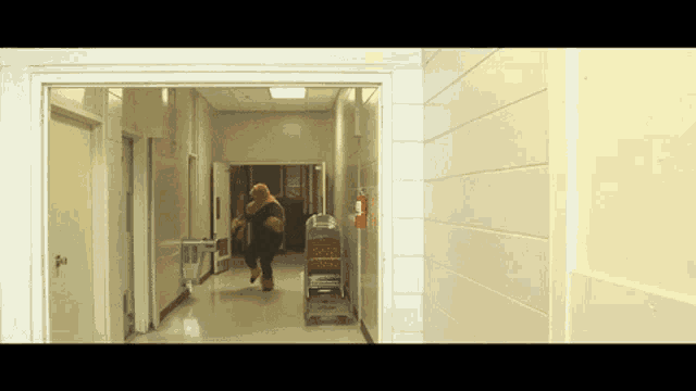 a person is running through a hallway with a red fire extinguisher on the wall
