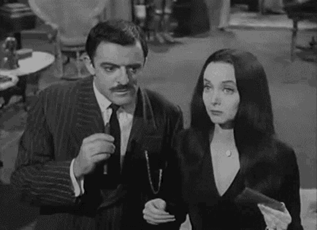 a black and white photo of a man and a woman standing next to each other in a room .
