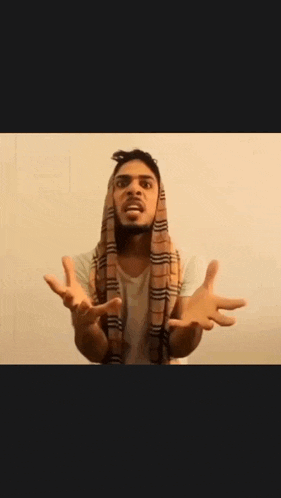 a man with a scarf around his neck is making a funny face with his hands in the air