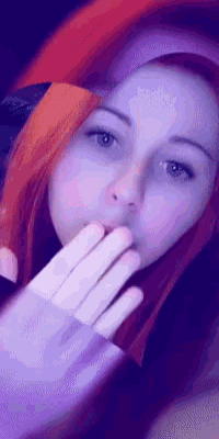 a woman with red hair is wearing a purple sweater