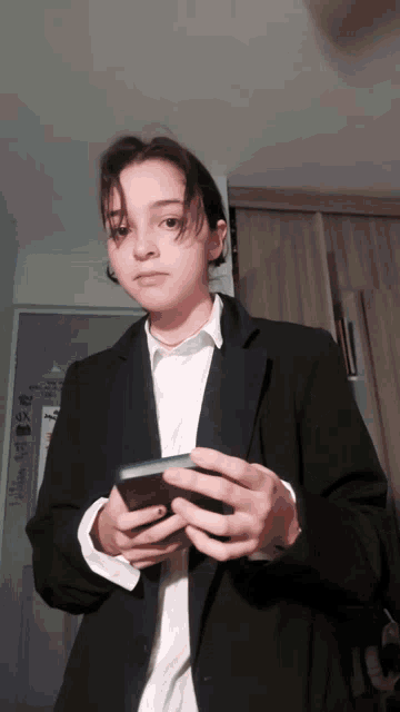 a woman in a suit holds a cell phone