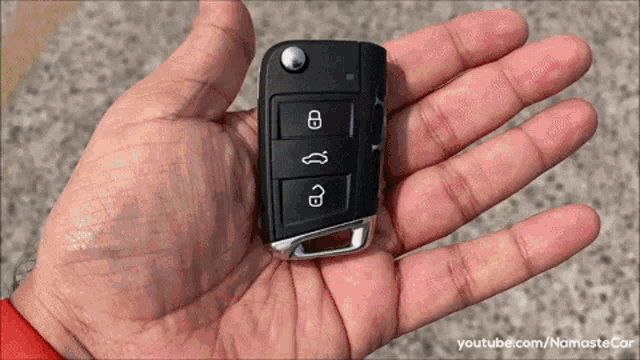 a close up of a hand holding a car key with youtube.com/namastecar written on the bottom