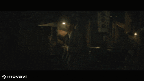 a man walking down a dark street with a sign that says movavi on the bottom