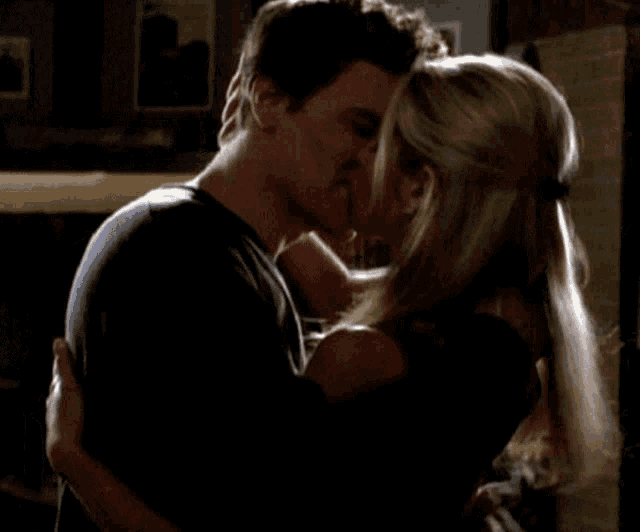 a man and a woman kissing in front of a fireplace