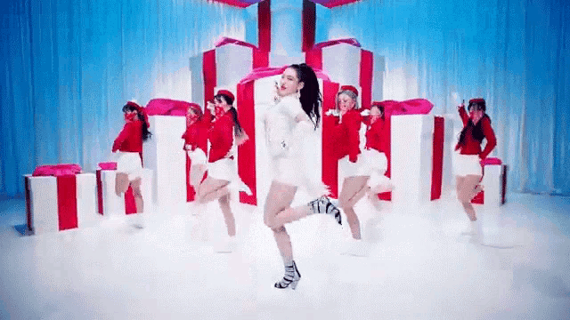 a group of women are dancing in front of christmas presents in a video .
