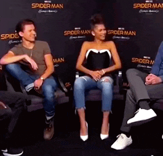 a man and a woman are sitting next to each other on a couch at a spider-man event .