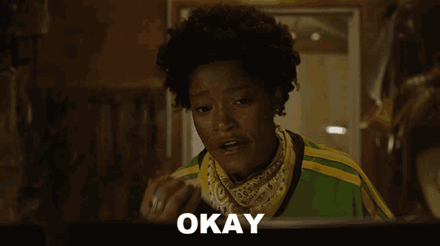 a woman in a green and yellow shirt talking on a walkie talkie with the word okay below her