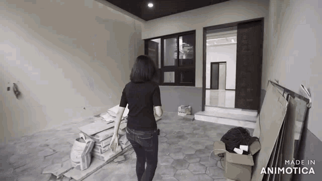 a woman in a black shirt is walking through a room with boxes on the floor and a sign that says made in animatica