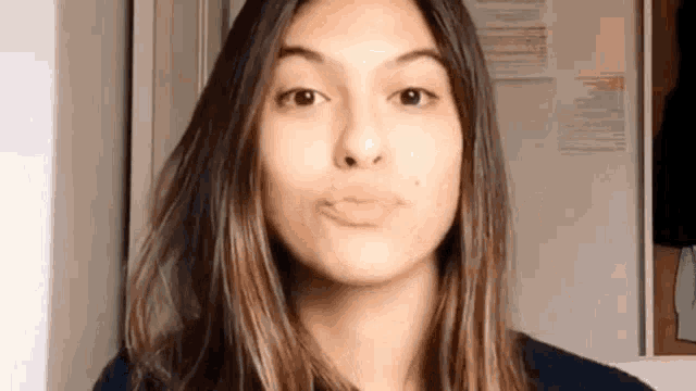 a woman with long hair is making a funny face while standing in front of a refrigerator .