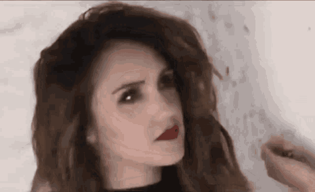 a close up of a woman 's face with red lipstick and long hair .