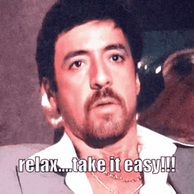 a man with a beard is wearing a suit and a necklace and says `` relax ... take it easy !!! ''