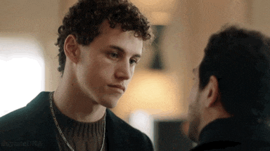 two men are looking at each other and one has curly hair