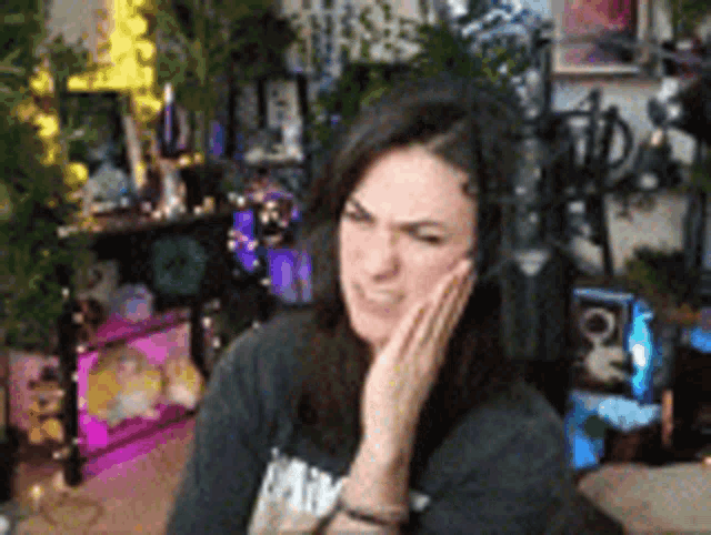 a woman is sitting in front of a computer screen with her hand on her chin .