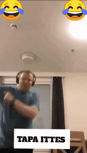 a man wearing headphones is dancing in front of a sign that says tapa ittens