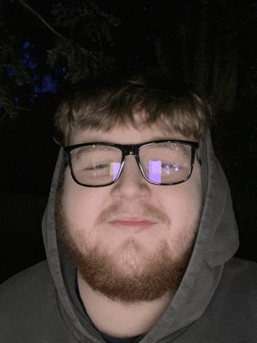 a man with a beard wearing glasses and a hood