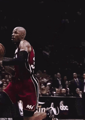 a man in a miami jersey is holding a basketball above his head
