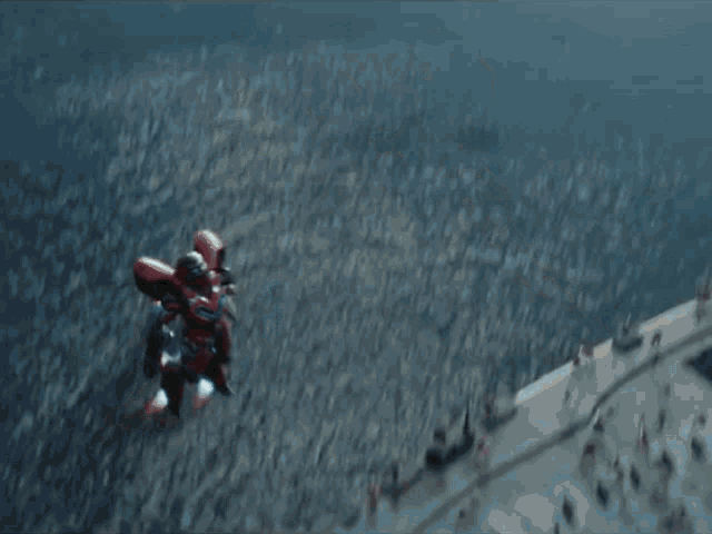 a red robot is flying through the air with a gun .