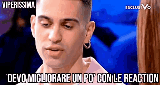 a man with a pink shirt and hoop earrings says " devo migliorare un po con le reaction "
