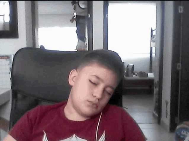 a young boy wearing a red shirt is sitting in a chair