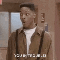 a man in a brown shirt and suspenders is standing in a hallway and says `` you in trouble '' .