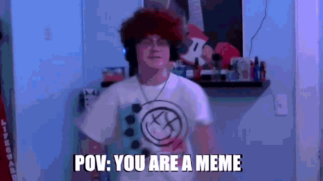 a man in a white shirt with a smiley face on it says " pov you are a meme "