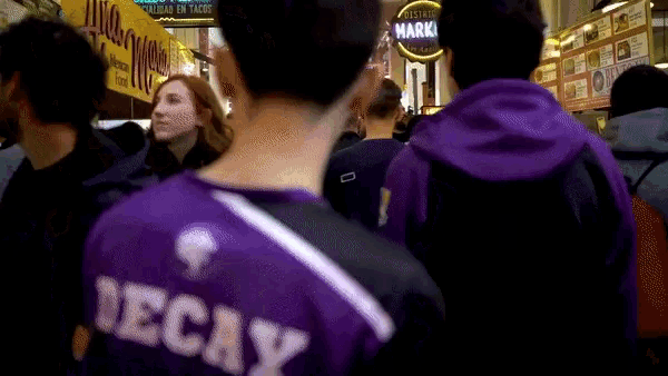 a man wearing a purple shirt that says decay on the back
