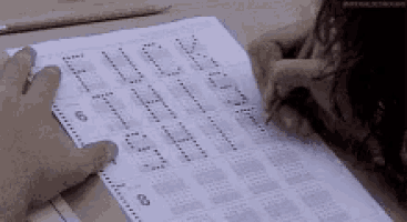 a person is writing on a piece of paper with the letters e i j k l m n o p q r