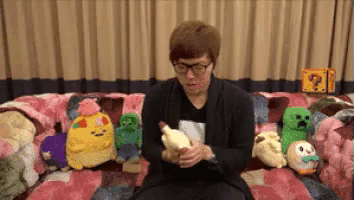 a man is sitting on a couch holding a stuffed animal in his hands