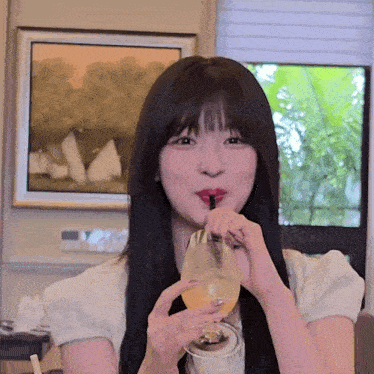 a woman drinking from a glass through a straw