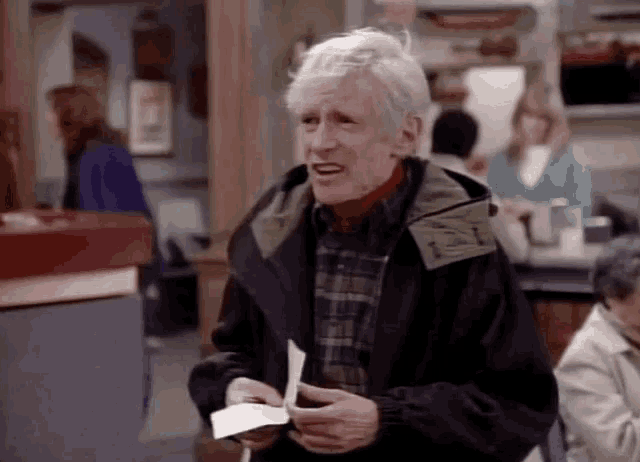 an older man in a black jacket is holding a piece of paper