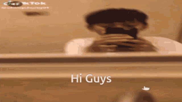 a man is taking a picture of himself in a bathroom mirror with the words hi guys on the bottom .