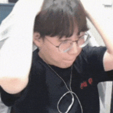 a young man wearing glasses and a black shirt is holding his head .