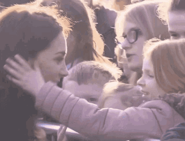 a little girl in a pink jacket is hugging a woman