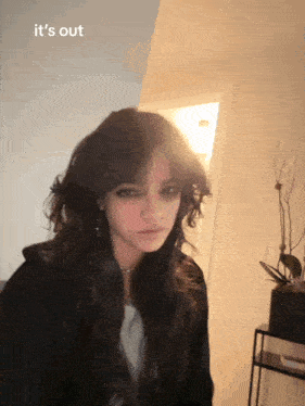 a girl in a black jacket with the words it 's out on the bottom