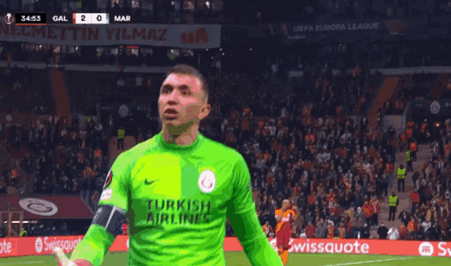a soccer player wearing a green turkish airlines jersey stands on the field
