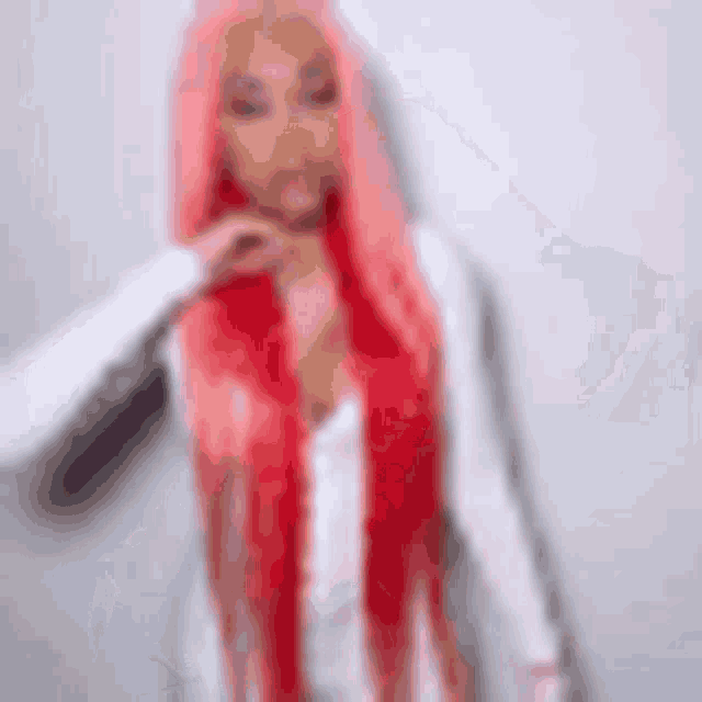 a woman with long pink hair is wearing a white shirt and red scarf .
